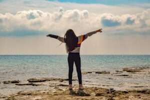 Woman standing on a beach looking at the ocean horizon, representing personal growth and business success.