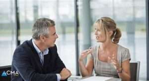 Professional coaching session showing a coach with a notebook engaging with a client to navigate business transitions.